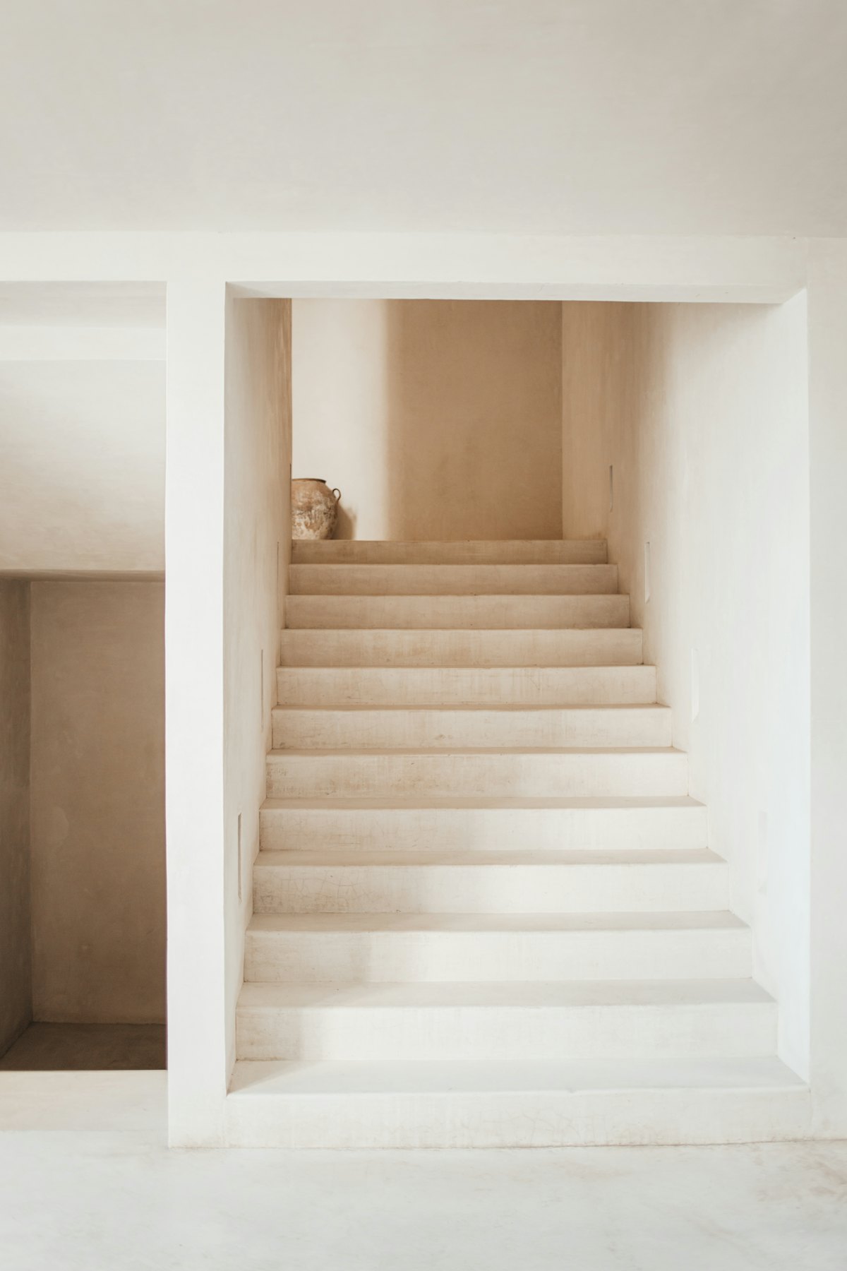 A pale minimal stairway lit by soft daylight.